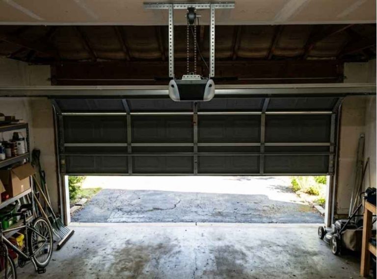 Interior view of a partially open garage door with overhead opener rail and daylight